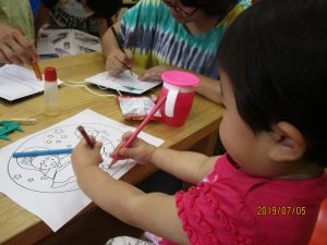 両手で色塗りをしているお子さんの様子